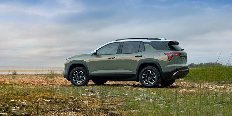 A green suv sitting parked in a field.