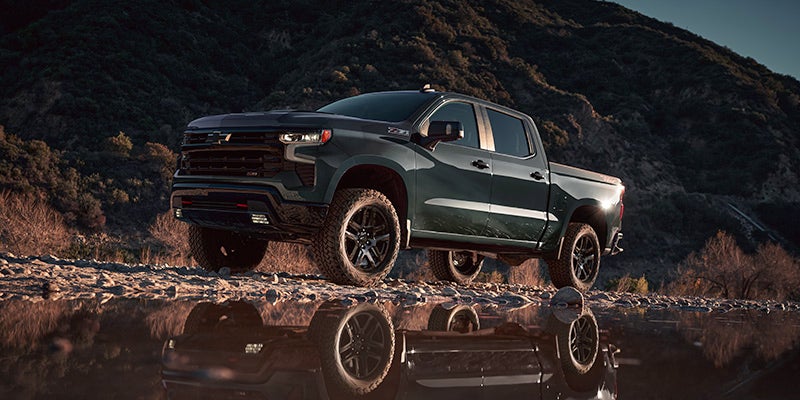 A green truck sitting parked in the dirt.
