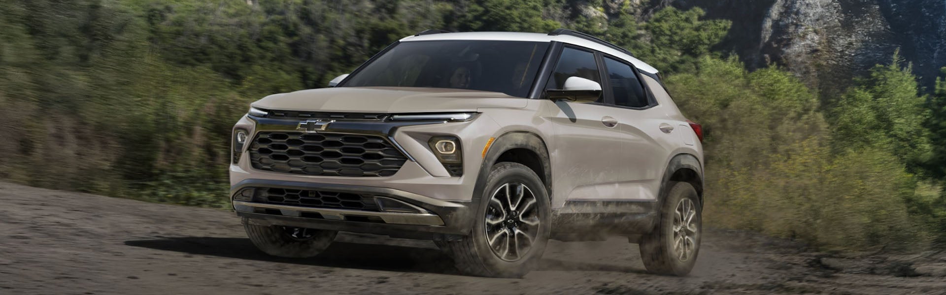 a beige 2026 trailblazer parked on a rocky terrain next to water