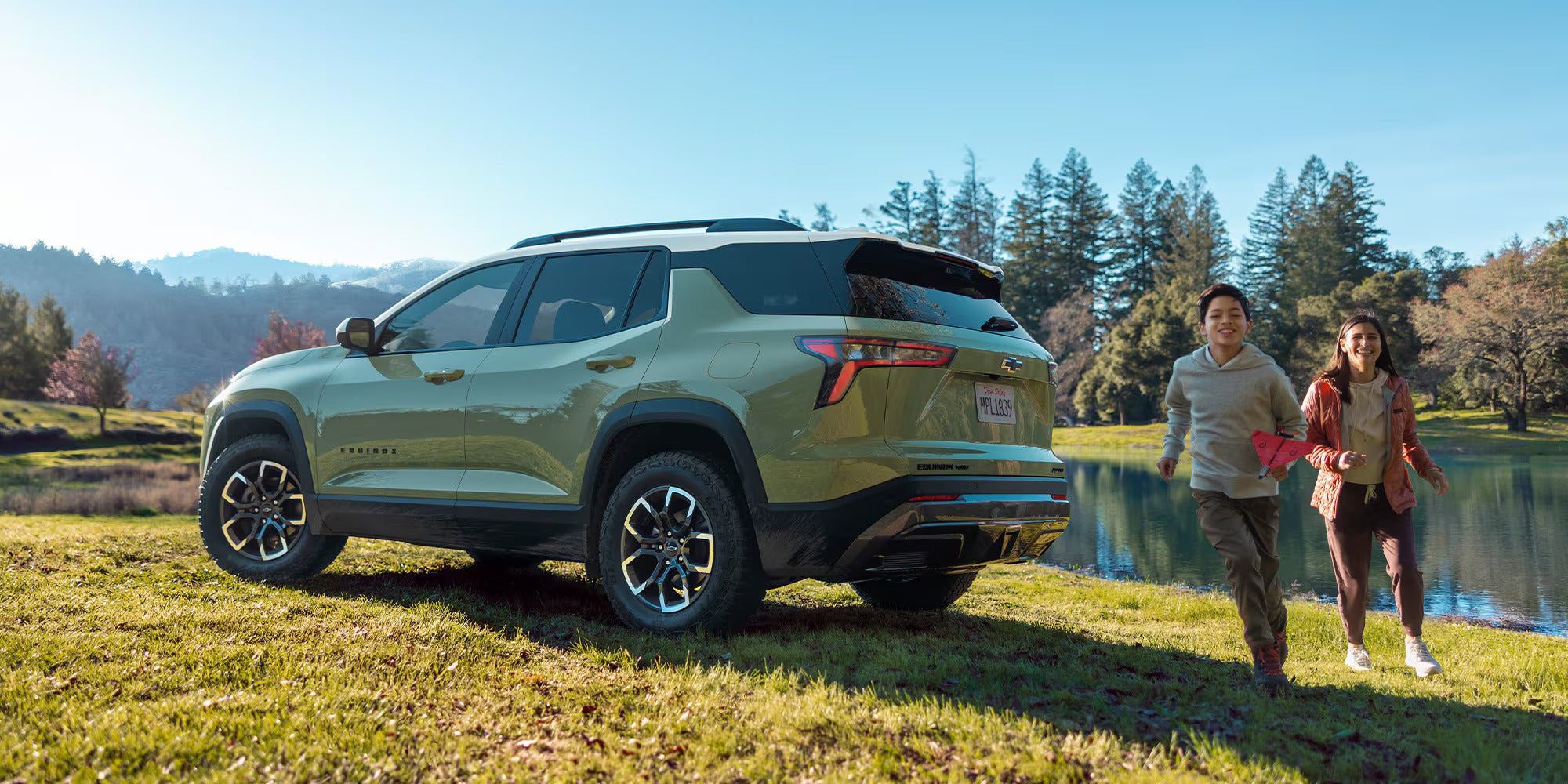 A green suv sitting parked in the grass.