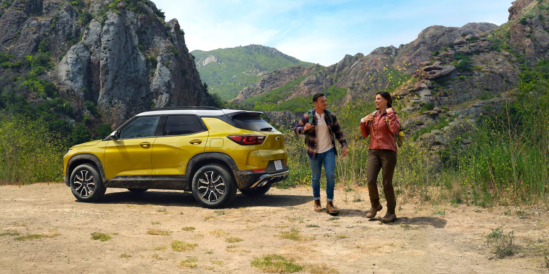 Two people next to a yellow suv.