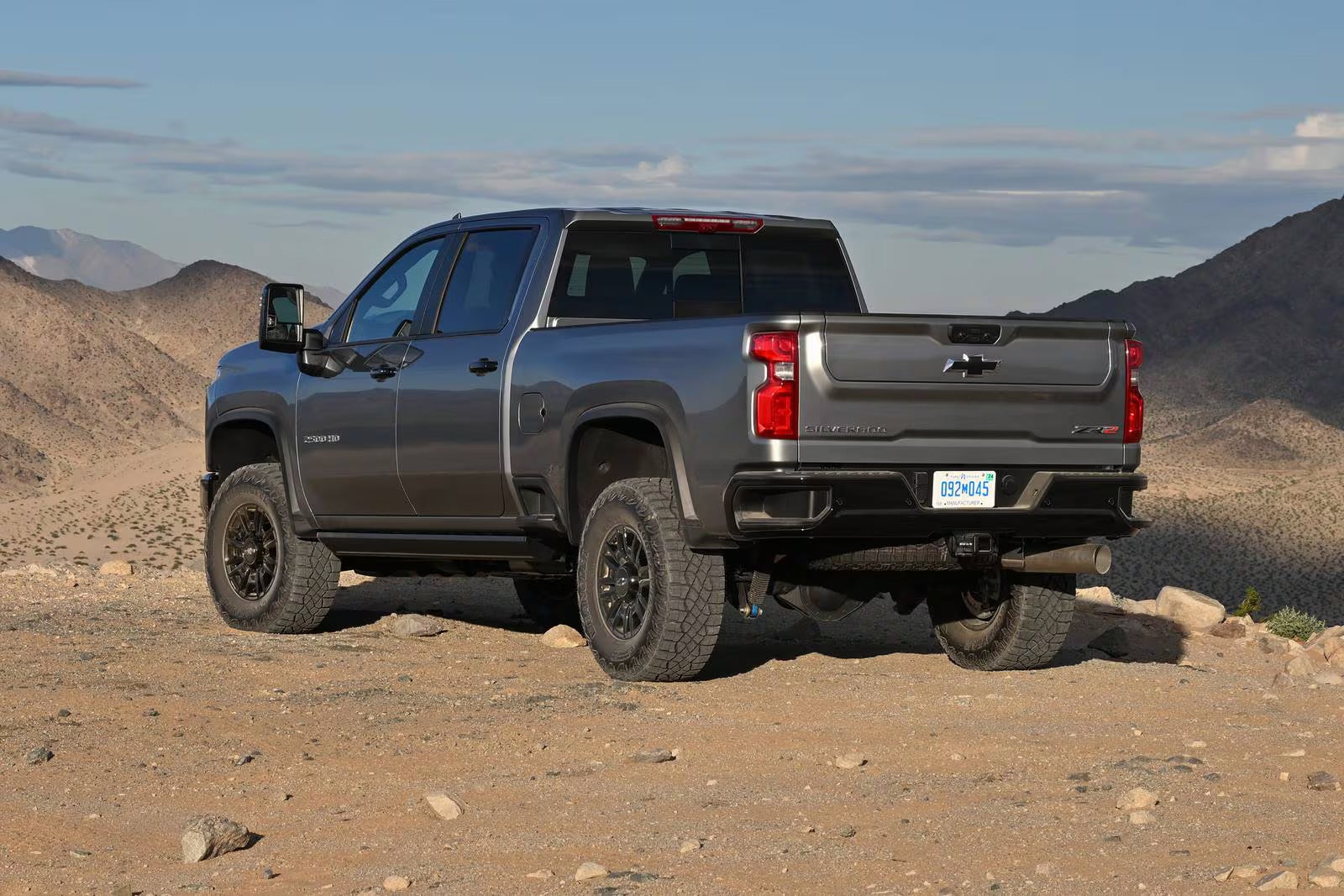 A gray truck sitting on a dirt road.