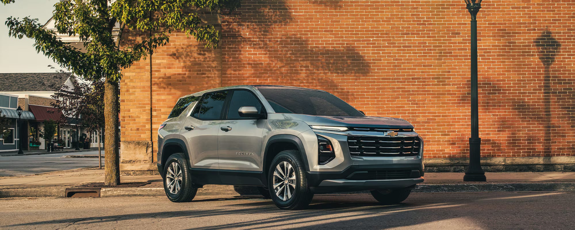 A gray suv parked in front of a brick wall.