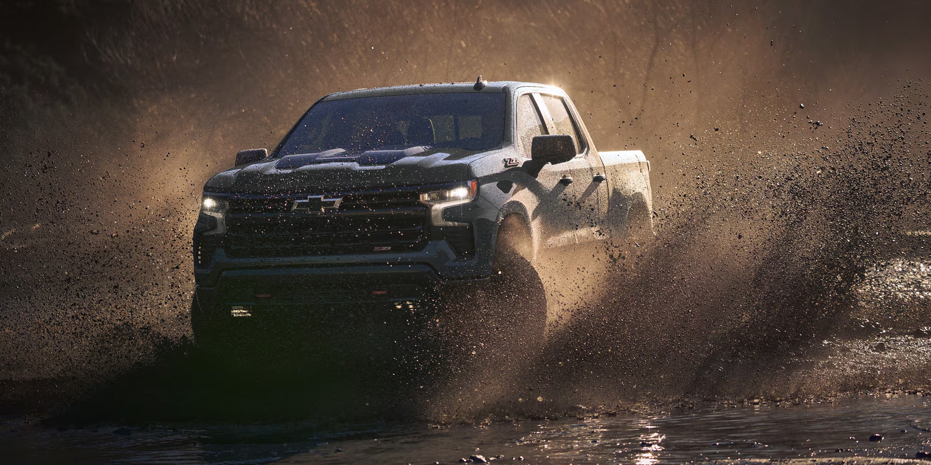 A chevy truck driving through the mud.