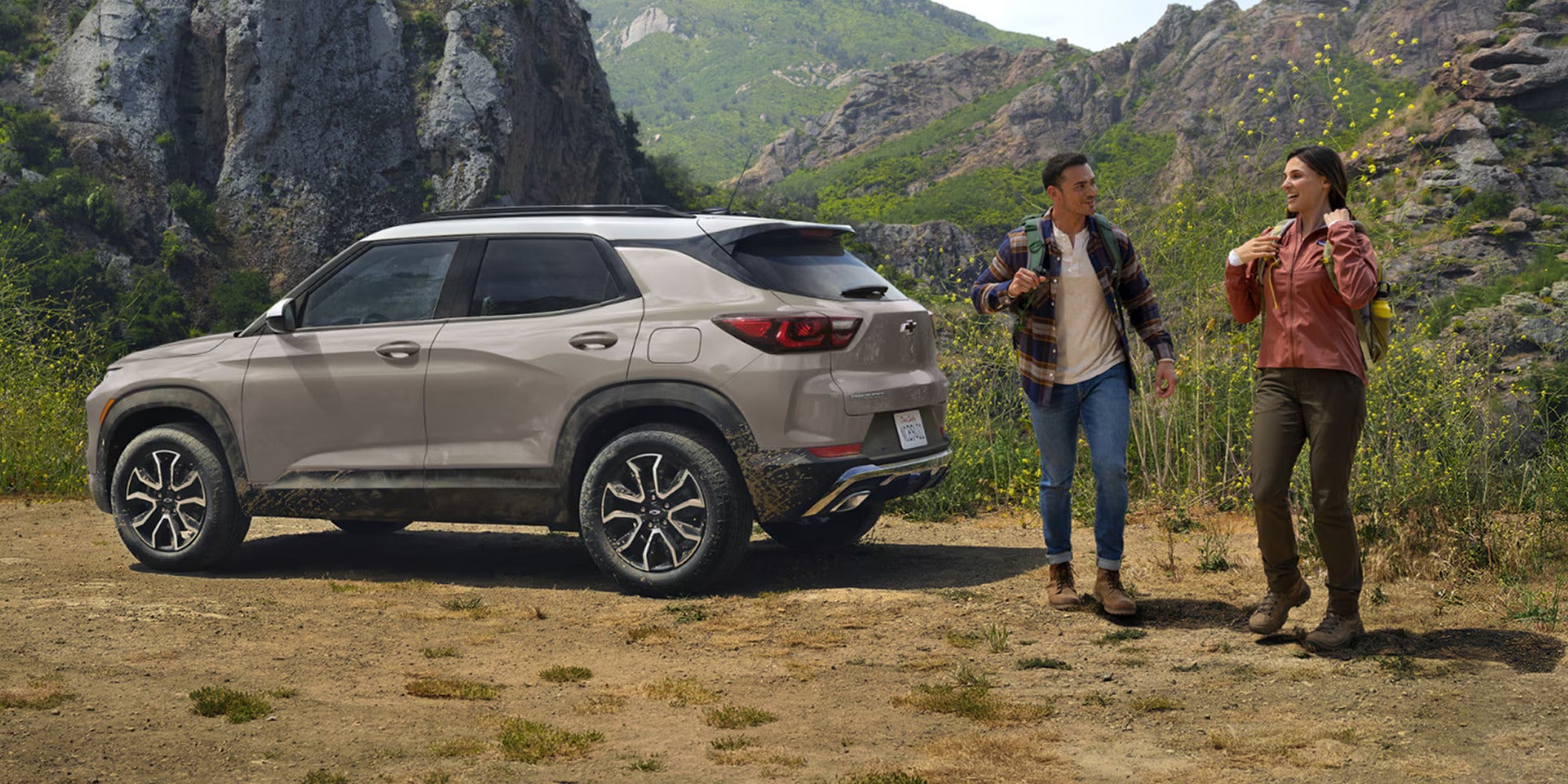 two people walking away from a parked chevy trailblazer in the mountains