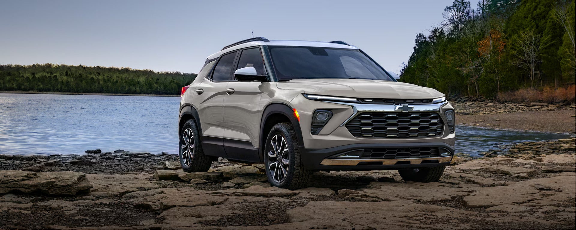 a beige 2026 trailblazer parked on a rocky terrain next to water