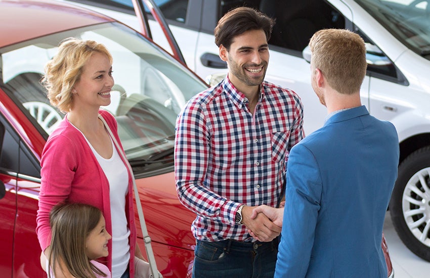 a family at a car dealership with a salesman